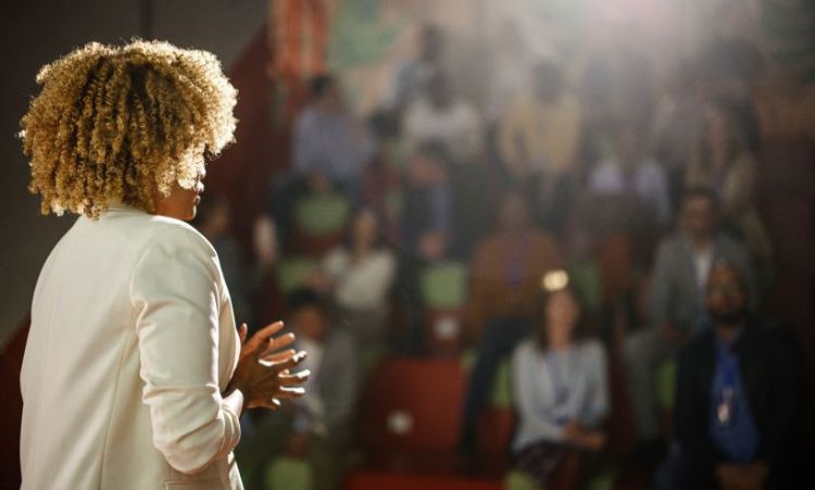 Woman presenting in front of a crowd